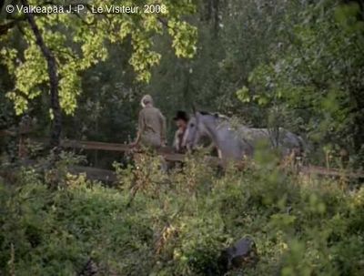 Le Visiteur, photogramme 75, plan 284, de retour de la visite à son Père. L'Enfant est surpris de voir sa Mère assise sur la clôture de l'enclos, en présence du Visiteur et de Son cheval.