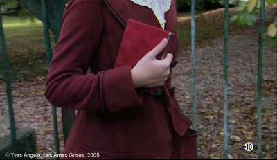   Les Âmes Grises  d'Yves Angelo.   Photogramme 27.  L'institutrice qui passe la grille du château, elle tient en main, le petit cahier rouge.