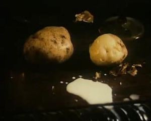 Photogramme - Lait 3 : Le Miroir, Plan 143.  Le lait tombe goutte à goutte sur les pommes de terre avec leurs épluchures.