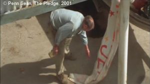 The Pledge  de Sean Penn.   Photogramme – 68.   1h 53’ 03’’. La banderole d’adieu du début du film : « Gonna fishing Jerry », traîne au sol. Jerry, titubant, la ramasse et la cache.