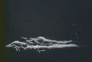 Photogramme - Lit : Nostalghia, Plan 35a. La femme enceinte du Poète allongée sur le lit, parallèle au mur.