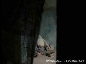  Le Visiteur, (Muukalainen), photogramme - plan 16, l'Enfant se dirige dans le coin de la chambre, mais la caméra reste au seuil de la chambre (5ème barrage). Il commence par enlever des planches du sol.