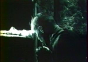 Photogramme - Fenêtre : Stalker, Plan 118. Le Stalker récitant le poème "Mais cela ne suffit pas." Remarquez les carreaux sombres de la fenêtre, qui traduisent des aspects sombres du Stalker. Ce plan est à comparer avec des plans du film Passions de Bergman, dans lequel Andréas est dans l'obscurité, et les fenêtres sont éblouissantes.